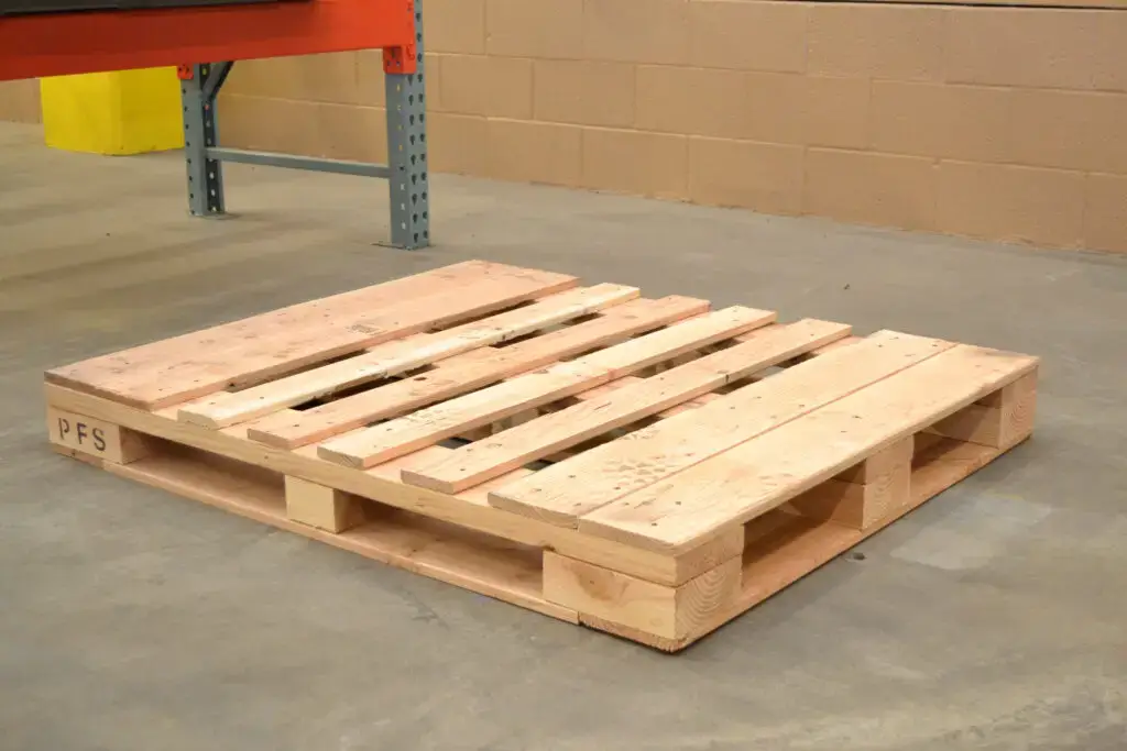 A single, custom wooden pallete sits on a concrete warehouse floor