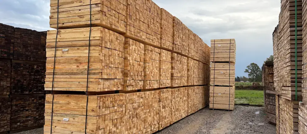 Stacks of precut pallet lumber sitting on a concrete pad outside.
