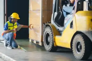 A Forklift driver loading a full shipping cargo container with his forklift.