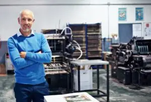 Man in professional warehouse setting standing beside quality control and supply chain equipment.