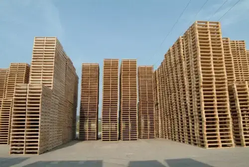 several tall stacks of pallets on concrete outdoors