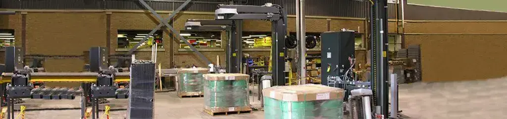 Stretch-wrapped pallet loads secured on a conveyor system in a packaging line.