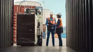Packaging specialists evaluating pallet performance and load stability in a shipping distribution environment.