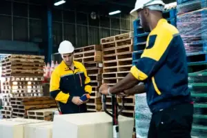 Supply chain professional evaluating pallet facts by comparing wood and plastic pallets in a warehouse operation.
