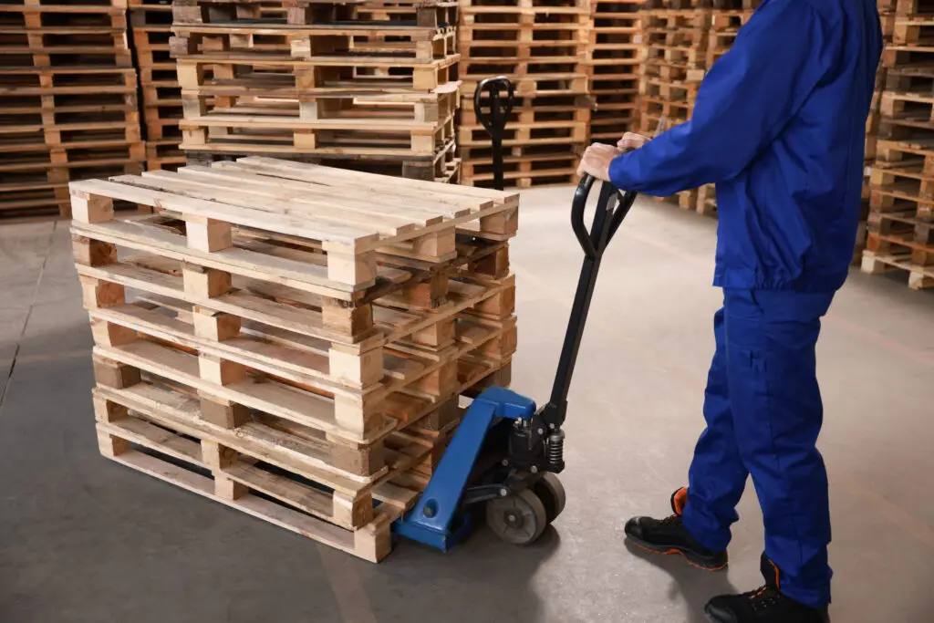 Workers safely handling standardized pallets showing how supply chain and supplier quality control through strategic sourcing can improve workplace safety