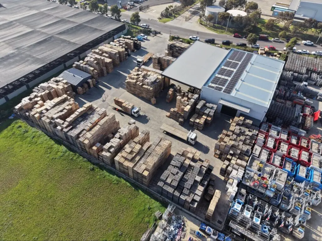 Aerial view of a pallet manufacturing facility with stacked lumber and finished pallets, illustrating vertical integration and supply chain resilience.