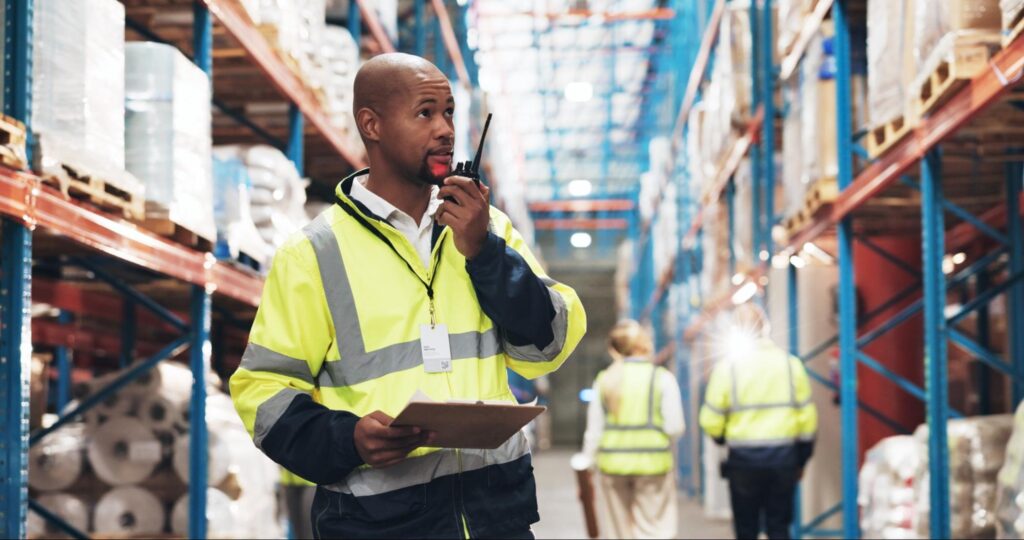 On-site logistics team member coordinating pallet shipments on a busy loading dock, representing single-point accountability in supplier risk mitigation.