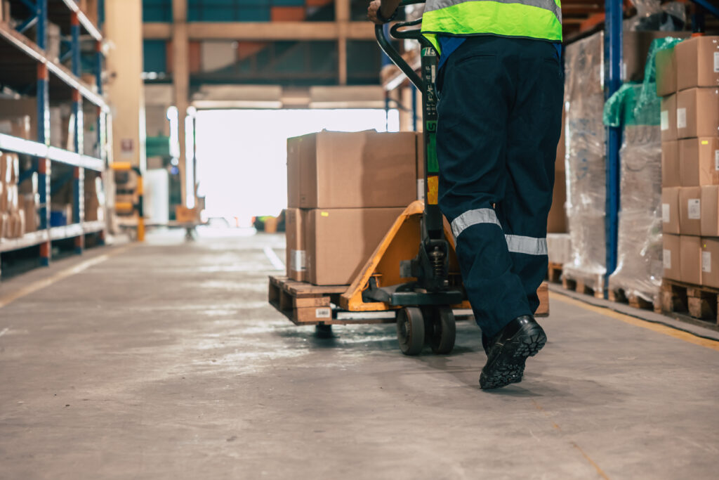 Forklift accessing a block pallet from the side in a distribution center, demonstrating the four-way entry that Costco and major retailers require.