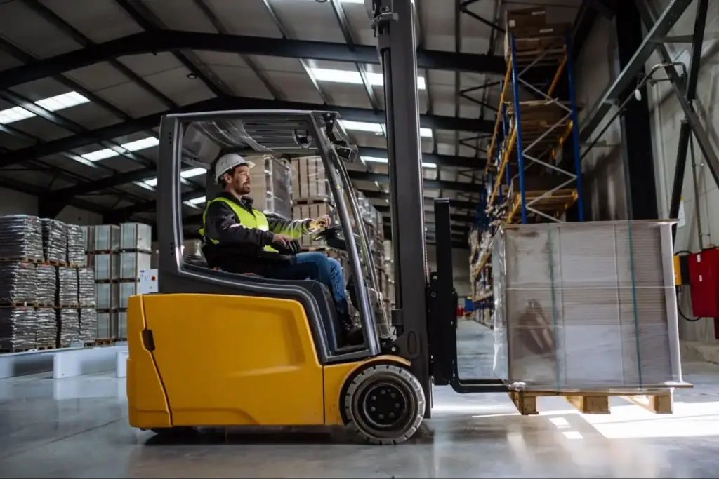 Forklift accessing a block pallet from the side in a distribution center, demonstrating the four-way entry that Costco and major retailers require.