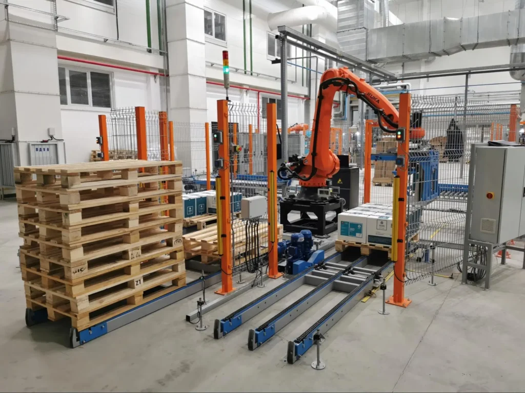 Robotic palletizer stacking product onto wood pallets inside an automated distribution center demonstrating supply chain automation in action.