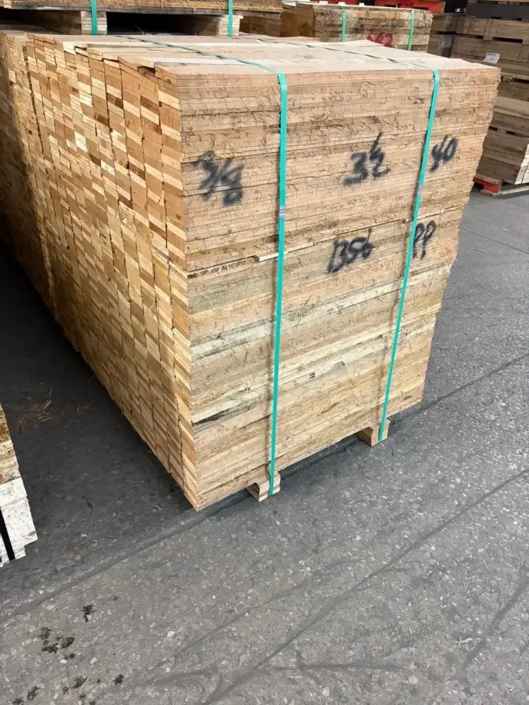 A rough-cut lumber stack with nominal lumber dimensions written on the surface, prior to kiln drying and planing that will reduce actual lumber dimensions from the original rough-sawn size shown here.