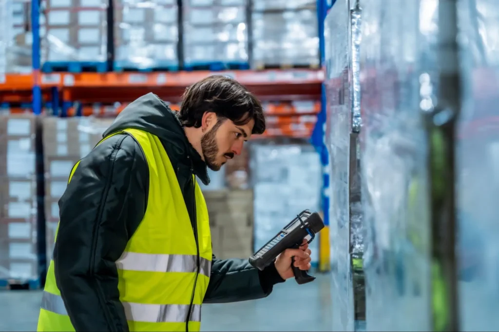 Food and beverage procurement professional inspecting standardized pallets in a warehouse, representing vendor consolidation and supply chain efficiency.