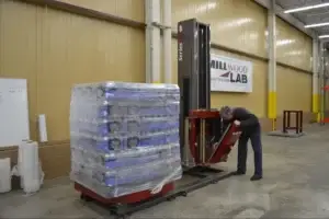 Millwood Lab technician inspecting a stretch wrapped unit load on a turntable stretch wrapper as part of end of line packaging maintenance for a customer.