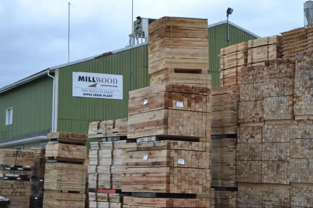 Stacked dimensional lumber in a Millwood industrial packaging facility showing the cross-sections of boards at various nominal lumber sizes, where the actual lumber dimensions after kiln drying and surfacing are visibly smaller than the nominal labels used to classify them.