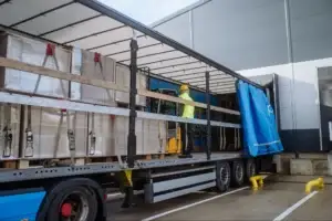 Warehouse Team Members inside a trailer organizing wooden dunnage boards between palletized loads, demonstrating how careful arrangement is required to fill gaps, prevent lateral movement and protect products during transit.